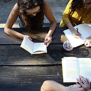 Three people studying at a table outdoors