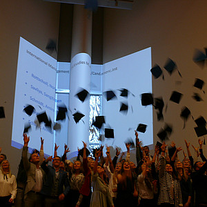 Absolventen im Audimax werfen ihre Hüte in die Luft