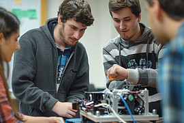 Eine Gruppe von Studierenden arbeitet an einem Fahrzeugmotor in einem Seminarraum