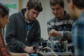 Eine Gruppe von Studierenden arbeitet an einem Fahrzeugmotor in einem Seminarraum