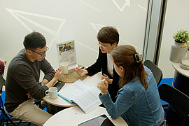 Gruppenarbeit von Studierenden an einem weißen Tisch in der Mensa der Europa Universität Flensburg.