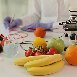 Verschiedene Obst Sorten liegen neben einem Mikroskop auf einem Tisch 