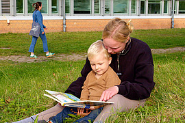 Weitaufnahme einer Lehramt Studierenden die einem Kind etwas vorliest. 