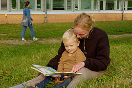 Weitaufnahme einer Lehramt Studierenden die einem Kind etwas vorliest. 