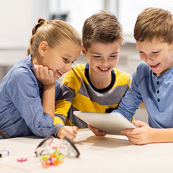 eine Gruppe lächelnder Kinder mit Tablet im Klassenraum 