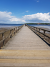 Bild eines Strandstegs, der zentral ins Bild hineinführt