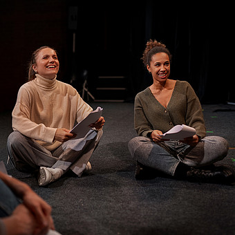 Zwei junge Menschen sitzen auf der Probebühne während eines Theater Seminars