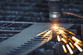Nahaufnahme eines Lasers auf Metall mit kleinen Funken