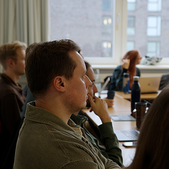 Mehrere Studierende sitzen in einem Seminar und hören der Lehrperson zu.