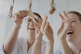 zwei lachende Studierende kochen selbstgemachte Pasta in Laborkittel in der Uni