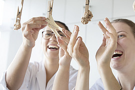 zwei lachende Studierende kochen selbstgemachte Pasta in Laborkittel in der Uni