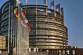 eine Weitaufnahme des Europa Parlaments, es wehen die Flaggen der EU Mitglieder in der Luft 