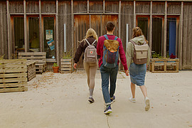 zeigt drei Studierende mit Rucksack am betreten der Campelle der Europa-Universität Flensburg 