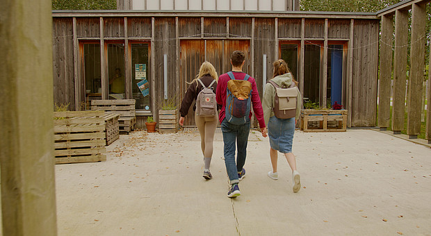 zeigt drei Studierende mit Rucksack am betreten der Campelle der Europa-Universität Flensburg 