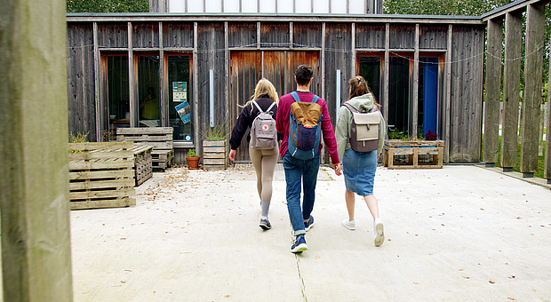 zeigt drei Studierende mit Rucksack am betreten der Campelle der Europa-Universität Flensburg 