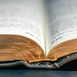 zeigt eine aufgeschlagene Bibel, mit nicht erkennbaren Inhalten 