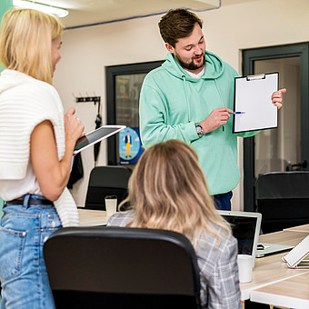 Eine Person im grünen Pullover erklärt Studierenden eine Theorie wöhrend eines Seminars 