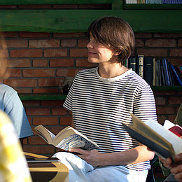 Fünf Studierende sitzen mit einer Bibel in einem Religionsseminar. Im Fokus steht eine junge Frau mit gestreiften Oberteil. 