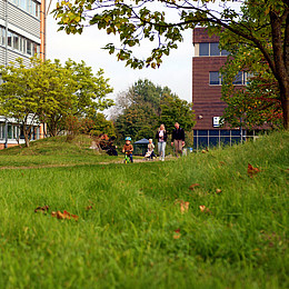 zeigt ein Kind auf einem Kindermobil auf einem Universitäts Campus 
