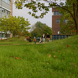 zeigt ein Kind auf einem Kindermobil auf einem Universitäts Campus 