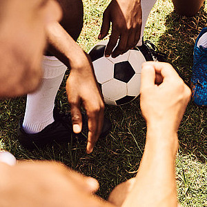 Eine Gruppe von Spielern mit einem Fußball, die eine Diskussion auf dem Feld führen