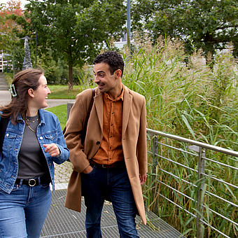 zwei Studierende der EUF gehen am grünen Campus entlang und diskutieren 