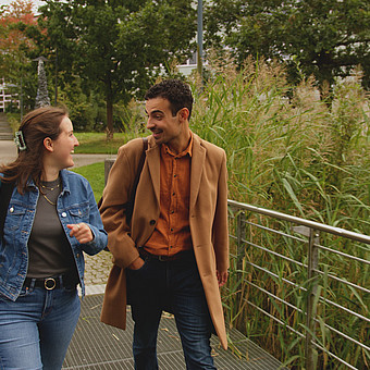 zwei Studierende der EUF gehen am grünen Campus entlang und diskutieren 