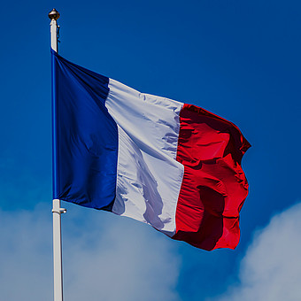 zeigt die Flagge von Frankreich im Wind unter blauem Himmel 