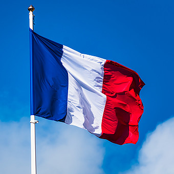 zeigt die Flagge von Frankreich im Wind unter blauem Himmel 