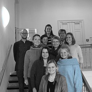 Gruppenfoto in schwarz/ weiß von neun Frauen und einem Mann auf einer Treppe.