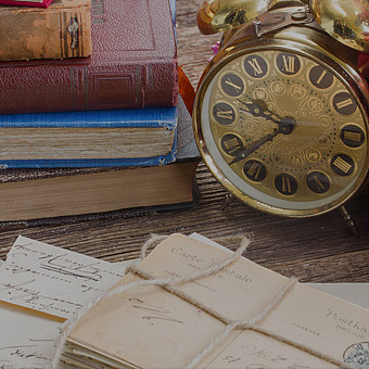 Nahaufnahme einer antiken Uhr auf einem Schreibtisch mit alten Briefen und Büchern. 