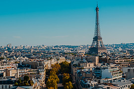 zeigt eine Luftaufnahme mit Eiffenturm von Paris unter blauem Himmel