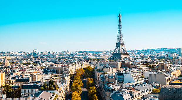 zeigt eine Luftaufnahme mit Eiffenturm von Paris unter blauem Himmel