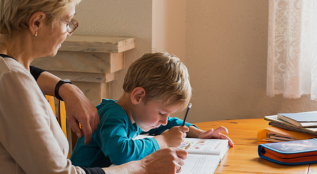 Ein Kind löst Schulaufgaben an einem Tisch mit Hilfe 