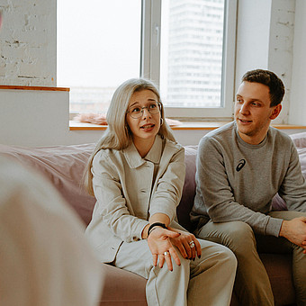 Eine Frau und ein Mann sitzen auf einem Sofa bei einer Beratung