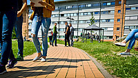 Hinter dem Gebäude Oslo der EUF sind viele Studierende auf den Spazierwegen unterwegs.