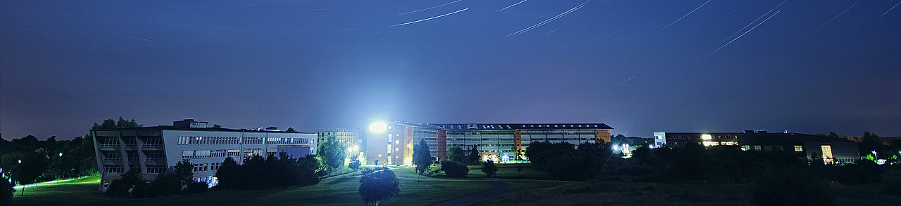 Campus bei Nacht mit Sternenspuren, die durch Langzeitbelichtung entstanden sind