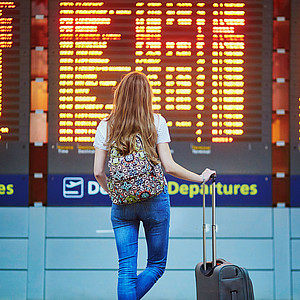 Junge Frau am Flughafen vor Infotafel