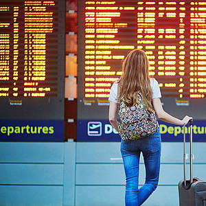 Junge Frau am Flughafen vor Infotafel