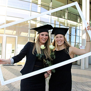 Zwei Absolventinnen des IIM-Studiengangs halten einen Bilderrahmen
