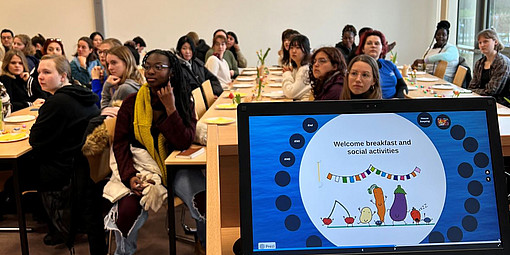 Studenten an Gruppentischen, im Vordergrund ein Laptop mit Präsentation