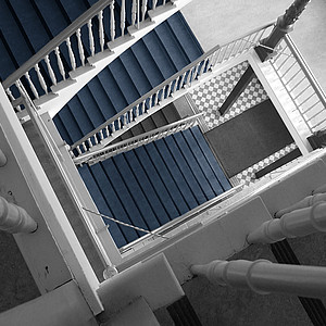 Schwarz/ weiß Foto von Treppenhaus aus Vogelperspektive mit blau akzentuierten Stufen.